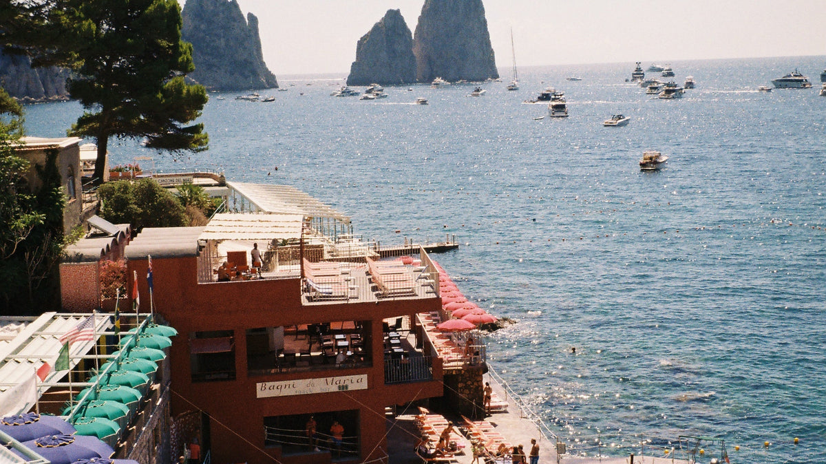 Marina Piccola, Capri, on 35mm film: striped beach umbrellas, Bagni da Maria and the Faraglioni rocks at sea