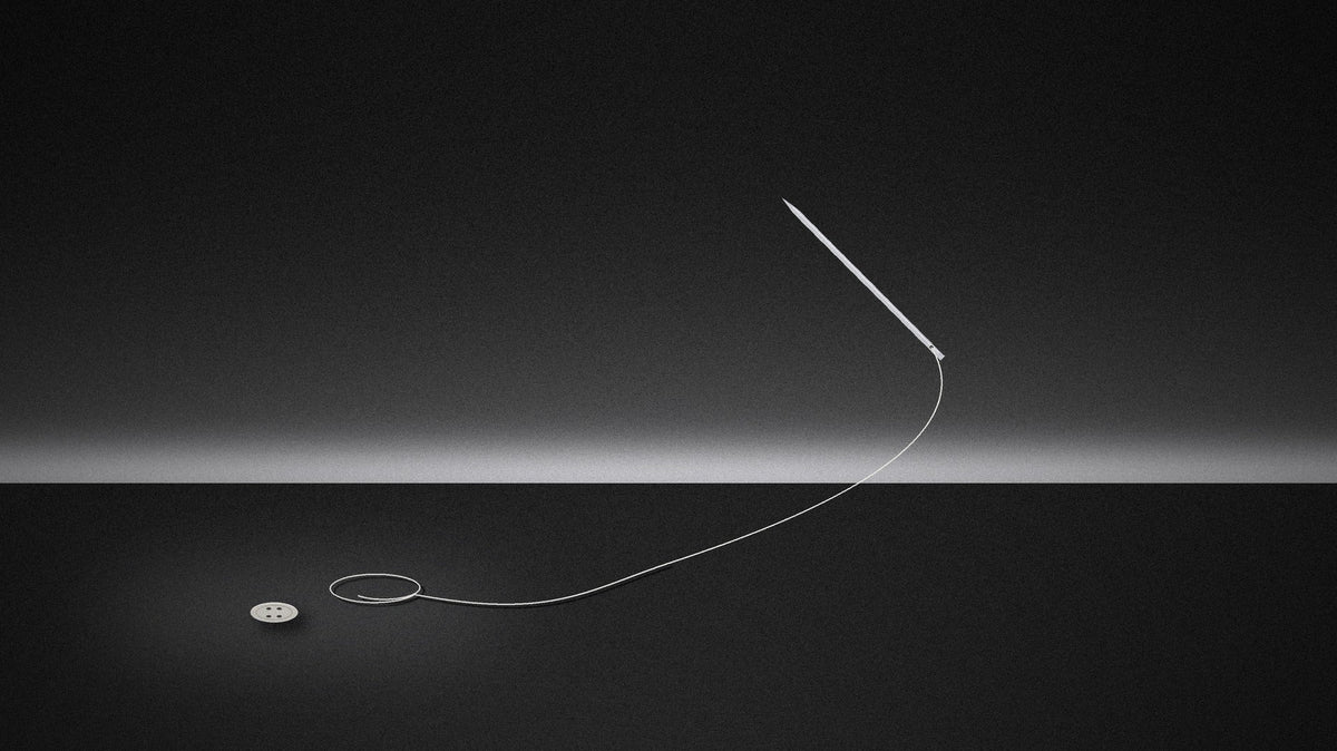 A needle and thread floating above a dark table, beside a single button
